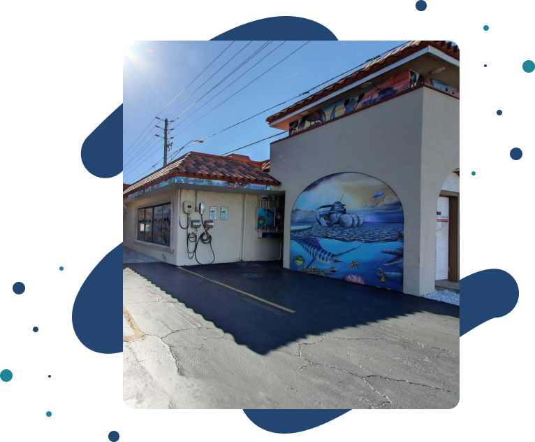 A building with a mural on the side and a parking lot in front of it.